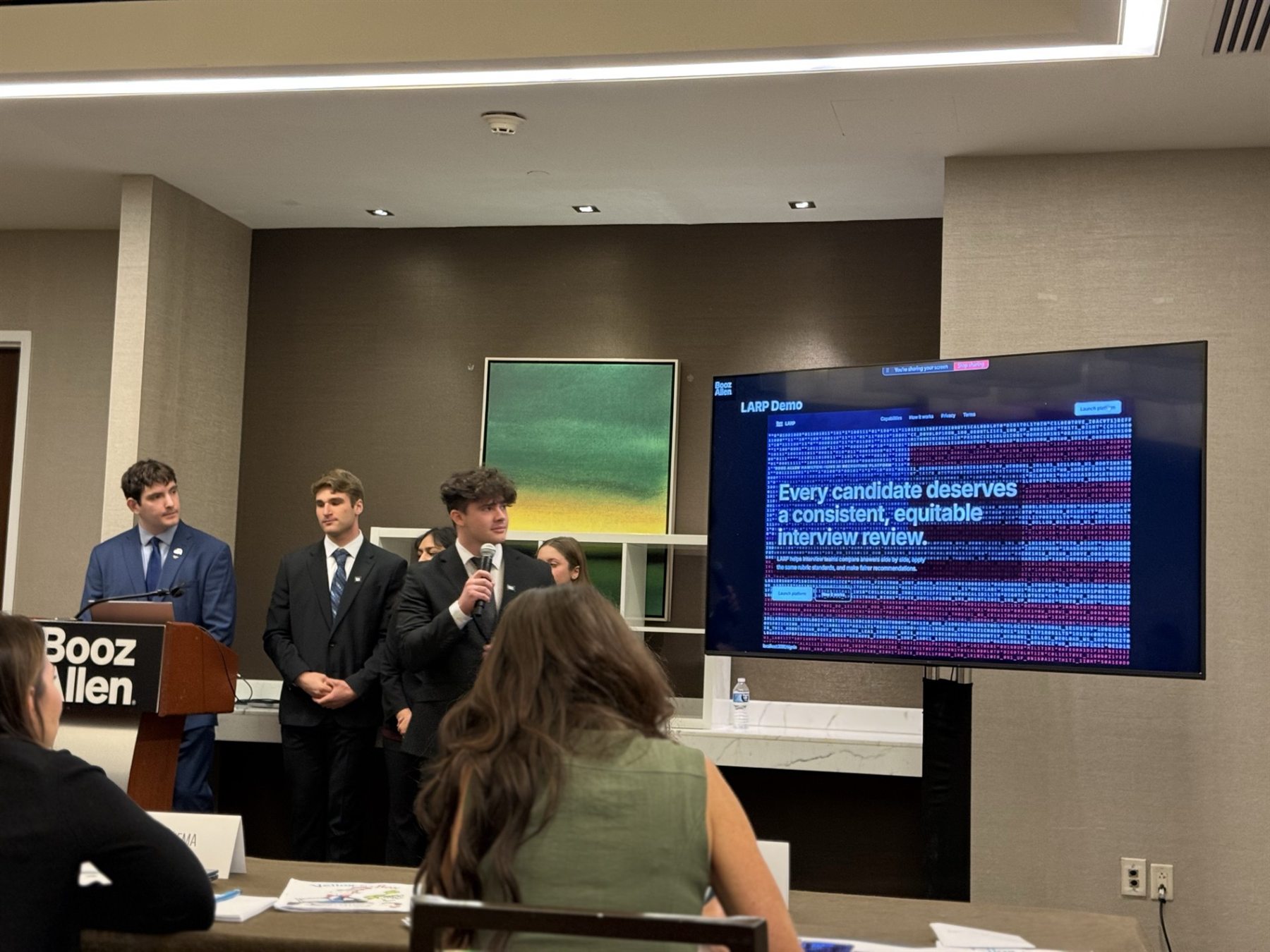 A student team presenting a live technical demo at Booz Allen