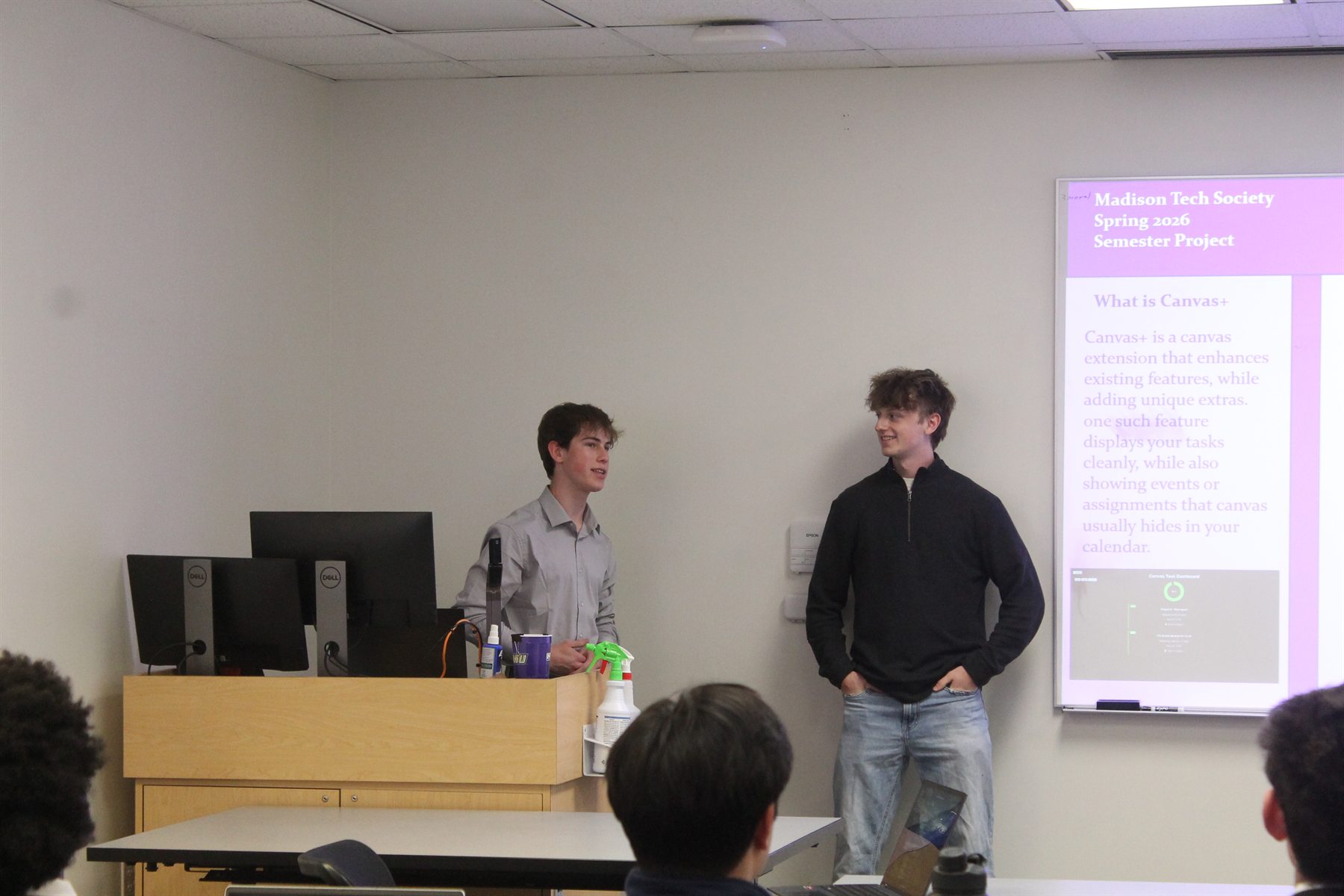 Two student presenters speaking beside a slide for the Canvas Plus semester project